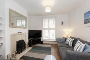 - un salon avec un canapé gris et une cheminée dans l'établissement Pepperpot Cottage, à Whitstable