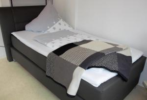 a bed with a black and white blanket on it at Ein gemütliches Zimmer an der Schweizer Grenze in Bietingen