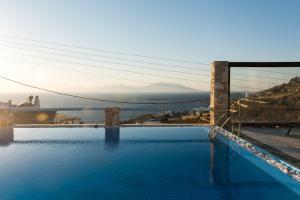 a bridge over a pool with a view of the ocean at Villa Boufla in Agios Ioannis Mykonos