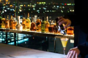 a person taking a picture of a bar with bottles of alcohol at ANA Crowne Plaza Kanazawa by IHG in Kanazawa