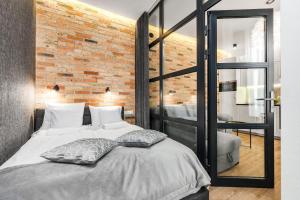 a bedroom with a brick wall and a bed with pillows at Happy Stay Apartments Osiek in Gdańsk