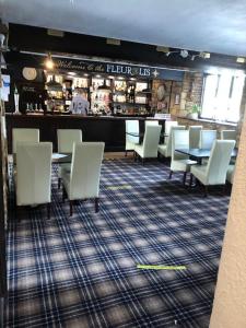 a restaurant with white chairs and tables and a bar at The Fleur-De-Lis Hotel in Chiselborough