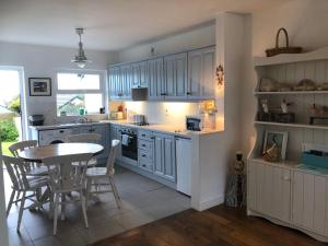 une cuisine avec des armoires bleues, une table et des chaises dans l'établissement Nanny Willow's Cottage, à Portballintrae