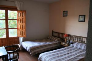 1 dormitorio con 2 camas, mesa y ventana en Casa Rural El Molino de Alocén, en Alocén