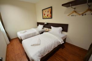 2 bedden in een hotelkamer met witte lakens bij 906 Riverside Hotel Malacca in Melaka