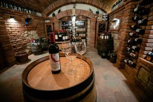 a bottle of wine sitting on a barrel with two wine glasses at Glodeanca in Glod