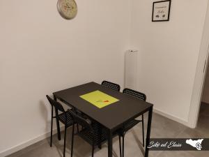 tavolo nero da pranzo con sedie e orologio sul muro di Sikè ed Elaia a Ragusa