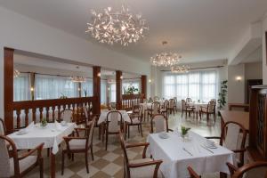 a restaurant with white tables and chairs and chandeliers at Villa Dr Szontagh Est. 1876 in Nový Smokovec