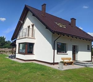 una casa blanca con un banco en un patio en STANLEJÓWKA, en Swornegacie