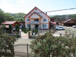 a house with a gate in front of a parking lot at Pensiunea Cetina in Brad