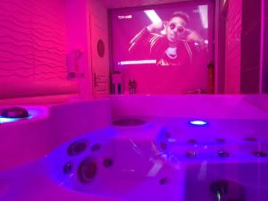 ein rosafarbenes Badezimmer mit einem TV und einer Badewanne in der Unterkunft Gites N Spa in Tourcoing