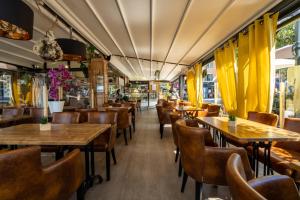 un restaurante con mesas y sillas de madera y cortinas amarillas en Hotel Restaurant Bellevue, en Bormes-les-Mimosas 52 fotos más