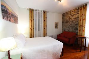 1 dormitorio con 1 cama blanca y 1 silla roja en Quinta do Serrado, en Porto Moniz