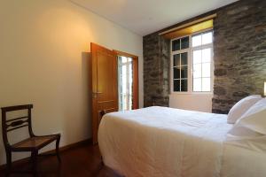 sypialnia z łóżkiem, krzesłem i oknem w obiekcie Quinta do Serrado w mieście Porto Moniz