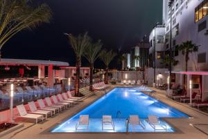 a pool with lounge chairs and a hotel at night at RV Park - Riverside Resort in Laughlin