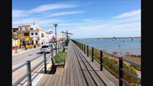 a boardwalk next to the ocean with cars parked on it at Ria Formosa Beach Apartment in Cabanas de Tavira