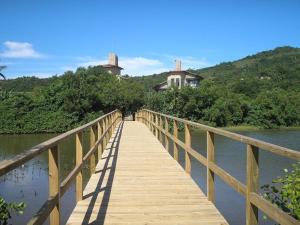 un pont en bois sur une nappe d'eau avec des maisons dans l'établissement Residencial Costa Esmeralda, à Florianópolis