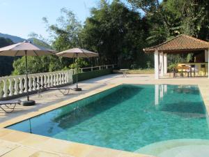a swimming pool with an umbrella and a gazebo at Pousada Princesa Isabel - Visconde in Petrópolis