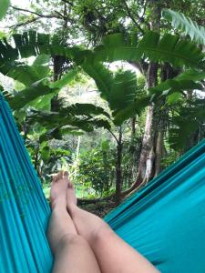 a persons legs laying on a hammock in a forest at Chalé Bela Vista - Chalés Belo Monte in Pacoti