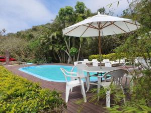 una mesa con sombrilla y sillas junto a una piscina en Pousada Porto do Arvoredo, en Florianópolis