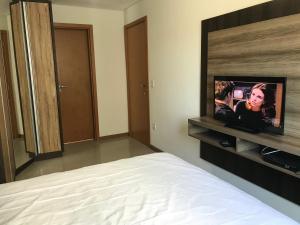 1 dormitorio con 1 cama y TV de pantalla plana en Flores de Veneranda, en Bombinhas