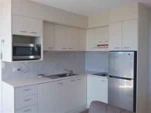 a kitchen with white cabinets and a stainless steel refrigerator at Mooloolaba Beachfront Apartment in Sandcastles in Mooloolaba