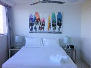 una camera da letto con un letto bianco con tavole da surf sul muro di Mooloolaba Beachfront Apartment in Sandcastles a Mooloolaba