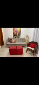 a living room with a couch and a red ottoman at Condomínio Summer House, Itacimirim in Itacimirim