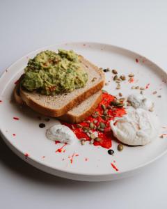 a white plate with a sandwich with guacamole on it at The Harvest Hotel in Cromwell