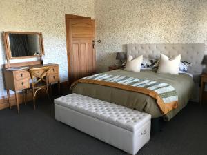 a bedroom with a bed and a table and a mirror at Cedar House in Gisborne