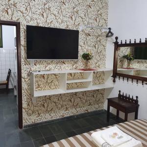 a living room with a television on a wall at Suíte 1, aconchegante, privativa e independente in Cuiabá
