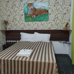 a bed in a room with a painting of a leopard at Suíte 1, aconchegante, privativa e independente in Cuiabá