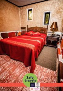 een slaapkamer met een bed met een rode deken bij Hotel del Carmen in Tlalpujahua de Rayón