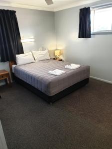 a bedroom with a bed with two towels on it at Civic Motel Grafton in Grafton