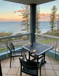 
a patio table with chairs and a table with a view of the ocean at Sea Point Ocean Apartments in Caloundra
