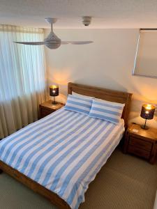 a bedroom with a bed with blue and white stripes at Sea Point Ocean Apartments in Caloundra