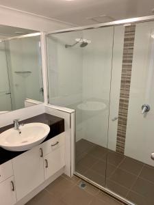 
a bathroom with a shower, sink, and mirror at Sea Point Ocean Apartments in Caloundra
