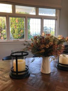 a table with a candle and a vase with flowers at Cedar House in Gisborne