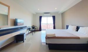 a bedroom with a bed and a desk and a television at B Space Residence in Nong Prue