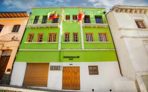 a green and white building with two flags on it at Colonial House Inn in Quito