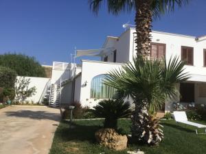 a white building with palm trees in front of it at Birgi holiday home in Marsala