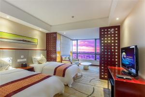 a hotel room with two beds and a flat screen tv at Haikou Mingguang Shengyi Hotel (Previous Mingguang International Hotel) in Haikou