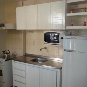 a kitchen with a sink and a white refrigerator at Ap Cote com Vista para Mar e Bicicletas in Maceió