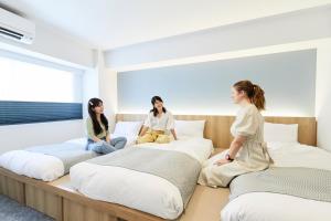 two women sitting on top of a bed in a hotel room at THE TOURIST HOTEL & Cafe AKIHABARA in Tokyo