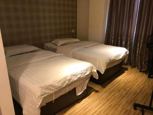 2 camas en una habitación con suelo de madera en My Family Hotel en Port Dickson