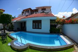 a swimming pool in front of a house at Suriya Arana in Negombo