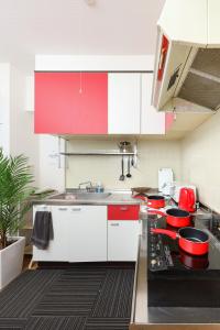 una cocina con armarios rojos y blancos y fregadero en Mezon Etowaaru, en Nagoya