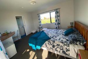 a bedroom with a bed with blue sheets and a window at White Elephant Accomodation in Motueka
