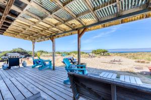 a wooden deck with blue chairs on the beach at Vinovilla in Rockaway Beach