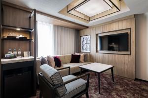 a living room with a couch and a tv at Solaria Nishitetsu Hotel Sapporo in Sapporo